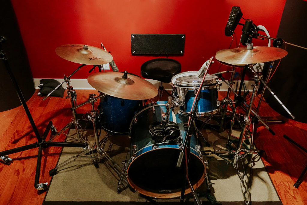 Drum set on a rug with a red wall in the background