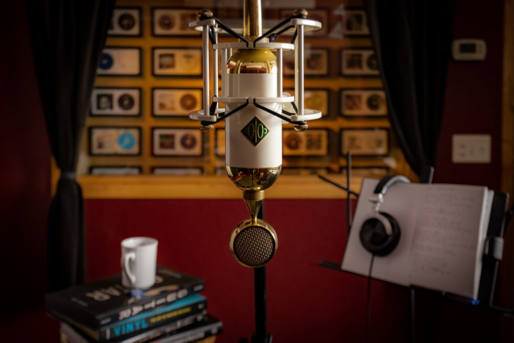 Close-up of a microphone with a coffee cup and writing notebook in the background